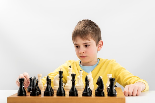 Premium Photo  Portrait of child during chess game boy plays chess and  thinks intently about the next move isolation on white background