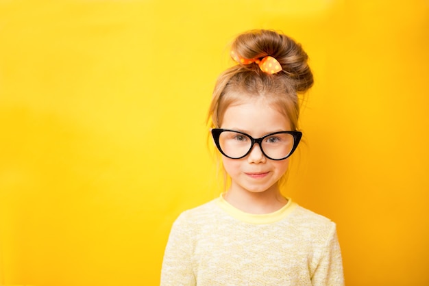 Портрет девочки в очках на желтом фоне. Копировать пространство