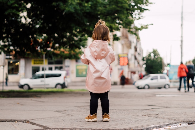 Portrait of child girl in pink raincoat outdoor