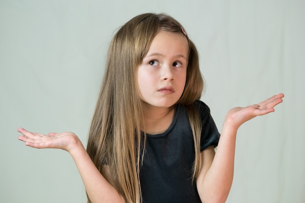 Portrait of child girl shrugging her shoulders making innocent I don't know expression.