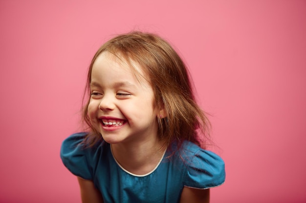 Портрет девочки с улыбкой, смотрящей в сторону на розовом изолированном фоне