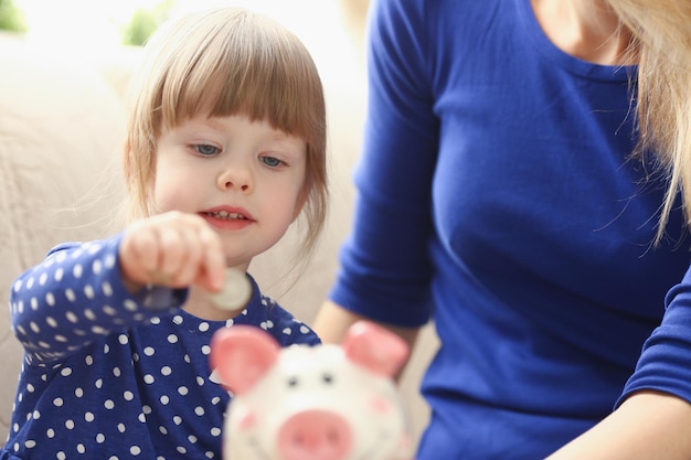 Portrait of child little girl putting coin money into piggy bank container. Making effective future needs savings, collect cash. Profit, savings concept