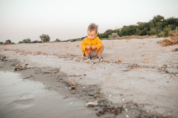 portrait of a child playing in the sand on the beach at sea at sunset