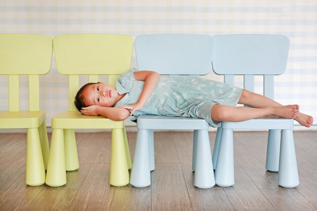 プラスチック製の赤ちゃん用の椅子に横になっている幼稚園の部屋で肖像画子幼児女の子。
