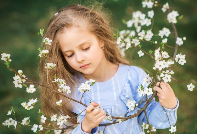 Portrait of a child's girl in a blooming garden. Spring photo. Flowers in your hair