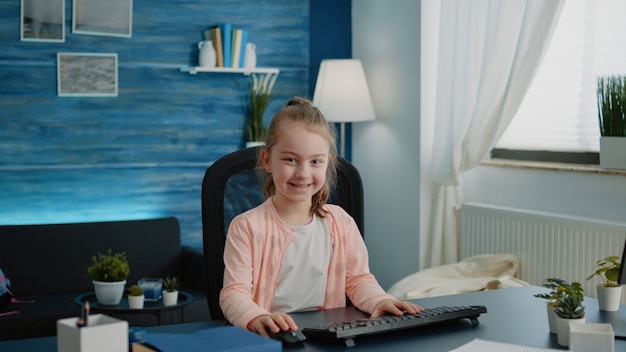 Portrait of child sitting at desk with computer for online lessons