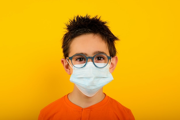 Portrait of a child with face mask for covid-19 coronavirus on yellow