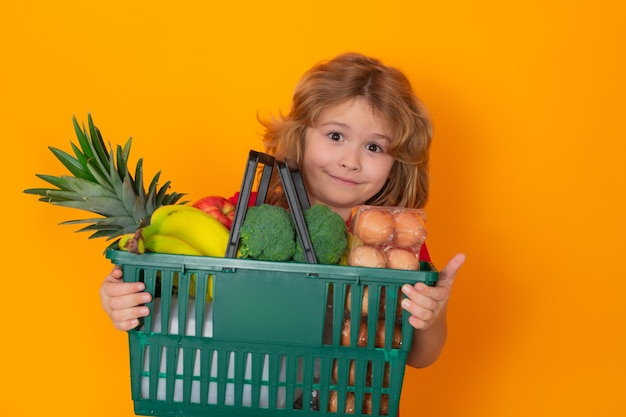 Portrait of child with shopping basket purchasing food in a grocery store