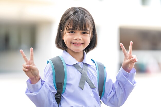 制服とバックパックで子供の学生の肖像画学校に戻るカメラを見て