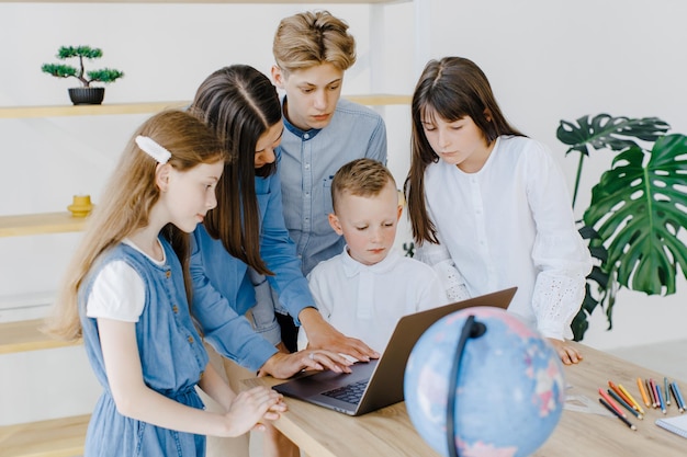 Portrait of children and teacher looking at laptop in the classroom