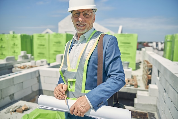 portrait of a civil engineer with a roll of paper smiling at the camera