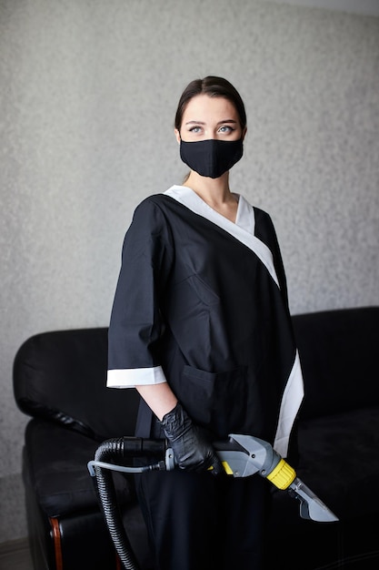 Portrait of cleaning service company employee removing dirt from furniture in flat with professional equipment Female housekeeper arm cleaning sofa with washing vacuum cleaner