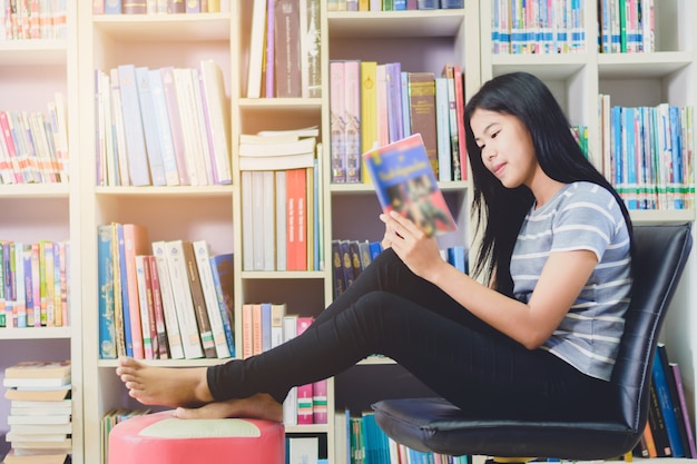 Portrait of clever Asian student reading and doing research in college library