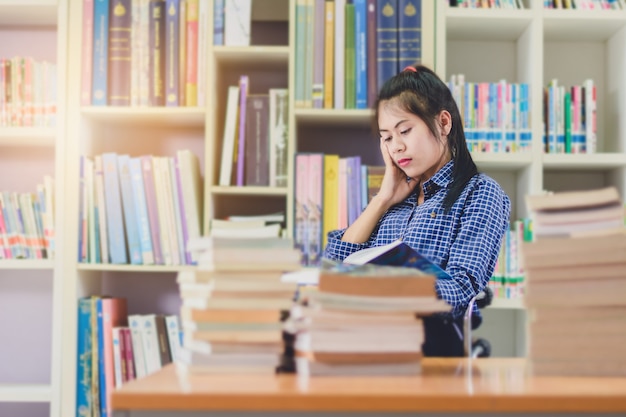 Portrait of clever Asian student reading and doing research in college library