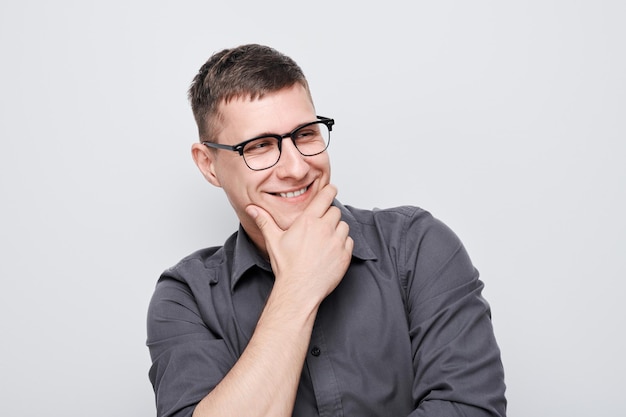 Portrait of clever man in shirt touching chin thinks doubts chooses isolated on white studio background with copy space