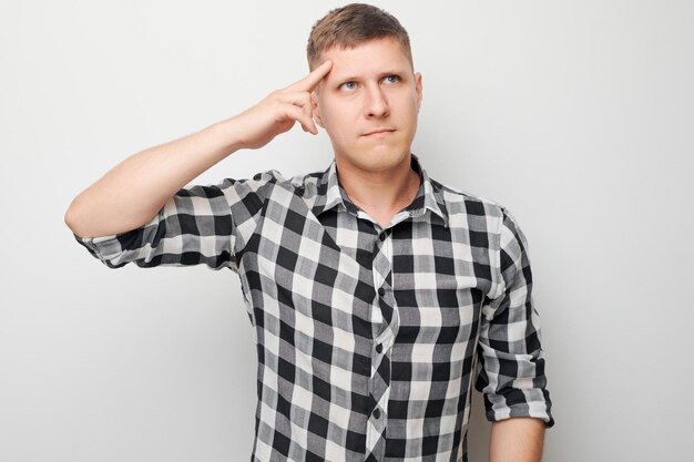 Portrait of clever man in shirt touching head thinks doubts chooses isolated on white studio background with copy space