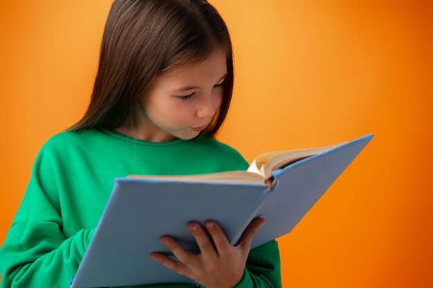 Portrait of clever teen girl with books against orange background