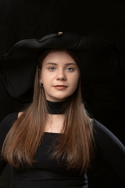 Portrait close up of young girl in black clothes and widebrimmed hat Young lady aristocrat