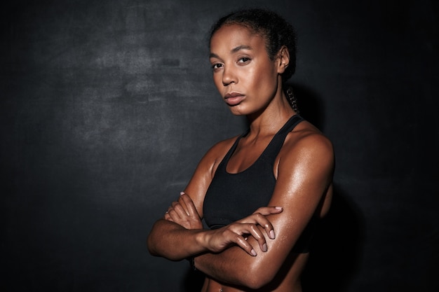 Portrait closeup of african american woman in sportswear standing isolated on black