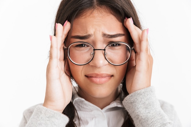 Portrait closeup of anxious frightened girl wearing eyeglasses crying and covering her face isolated over white wall