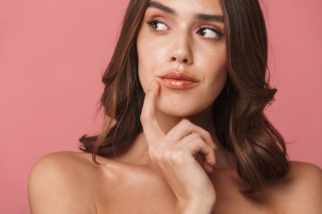 Portrait closeup of brooding shirtless brunette woman looking aside at copyspace 