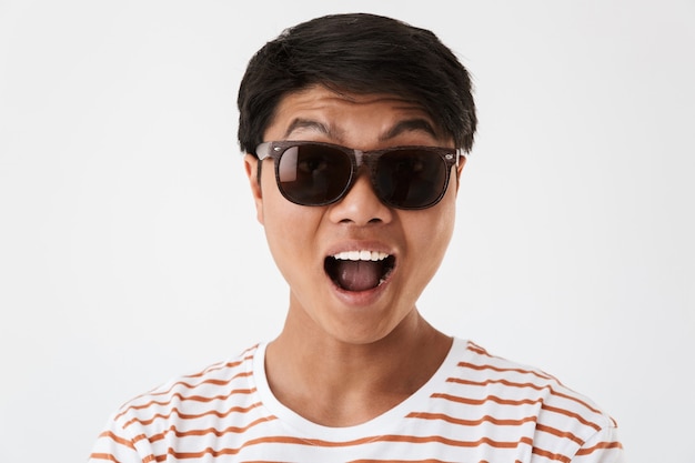 Photo portrait closeup of positive chinese man wearing striped t-shirt and black eyeglasses smiling or screaming and looking at you, isolated. concept of emotions