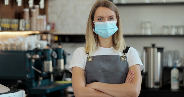 Portrait of coffee shop restaurant woman in face medical protection mask, office worker, coronavirus quarantine is over. Small business after covid.