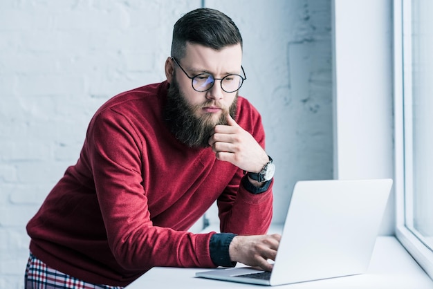 Portrait of concentrated businessman in eyeglasses working on laptop