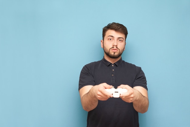 Portrait of a concentrated gamer with a joystick in his hand on blue