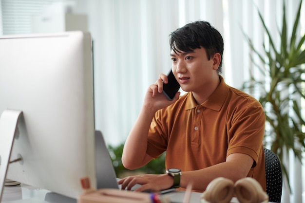 Portrait of concerned developer calling coworker asking to fix bugs in released project