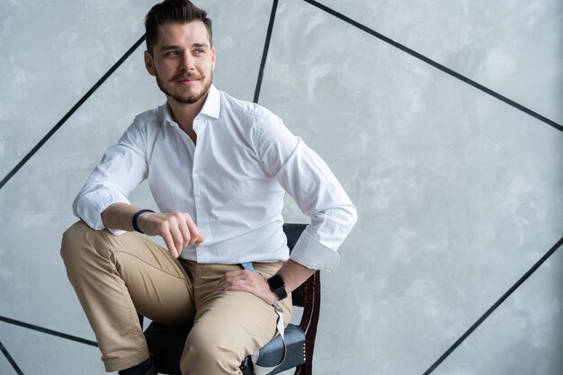 Portrait of confidence. Full length of thoughtful young man in full suit looking away while sitting on the stool.