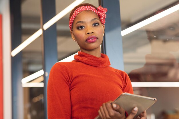 Portrait of confident african american businesswoman with digital tablet in creative office