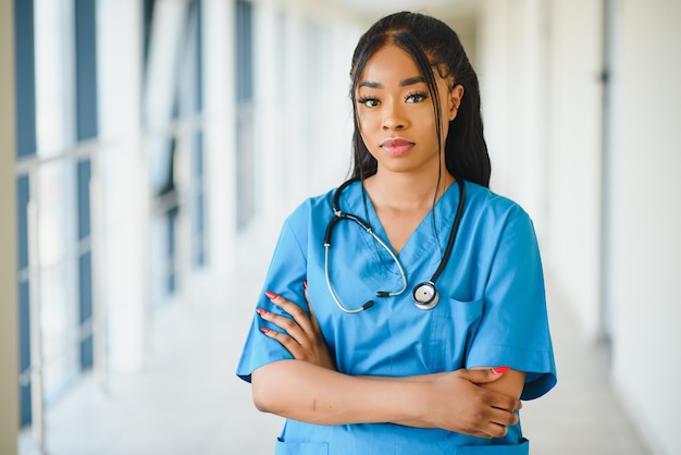 Ritratto fiducioso afroamericano medico femminile medico professionista scrittura note paziente isolate su priorità bassa di finestre corridoio clinica ospedale. espressione positiva del viso