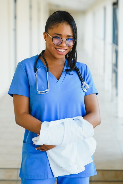 Ritratto fiducioso afroamericano medico femminile medico professionista scrittura note paziente isolate su priorità bassa di finestre corridoio clinica ospedale. espressione positiva del viso