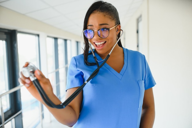 초상화에 자신감이 있는 아프리카계 미국인 여성 의사 의료 전문가는 병원 클리닉 복도 창문 배경에 격리된 환자 메모를 작성합니다. 긍정적인 표정