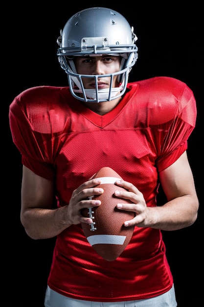 Portrait of confident American football player holding ball