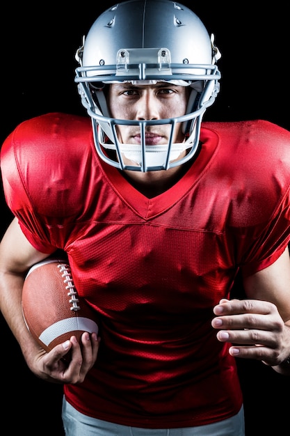 Portrait of confident American football player running while holding ball