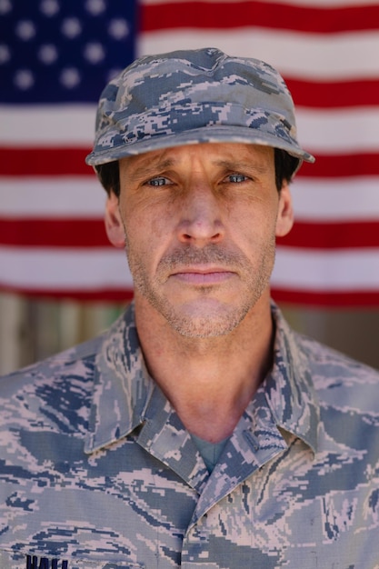 Foto ritratto di un soldato dell'esercito fiducioso che indossa berretto e uniforme mimetica contro la bandiera degli stati uniti. persone, patriottismo e concetto di identità, inalterati