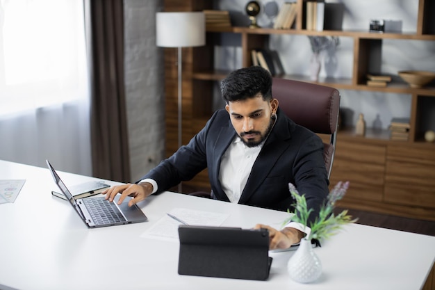 Portrait of a confident bearded man working at home with laptop on some project