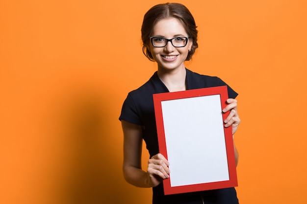 Portrait of confident beautiful young business woman holding blank photo frame in her hands