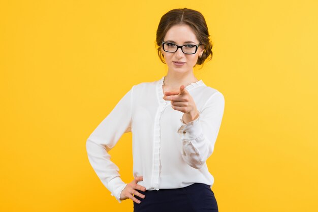 Portrait of confident beautiful young smiling happy business woman showing on client on yellow background