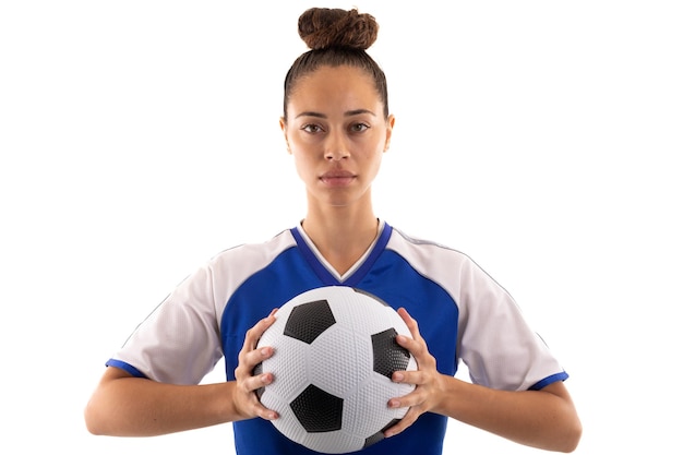 portrait of confident biracial young female soccer player with soccer ball against white background