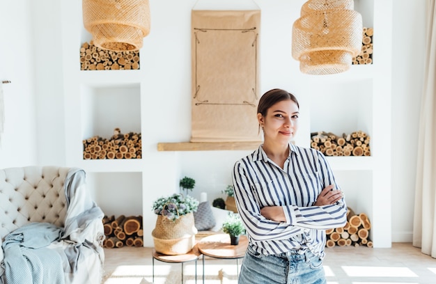 Portrait of confident business woman standing in modern living room with crossed arms and looking on camera.