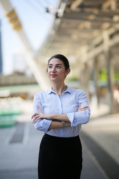 portrait confident business women standing with arm cross against city