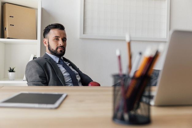 Foto ritratto di un uomo d'affari fiducioso che guarda la telecamera mentre è seduto sul posto di lavoro