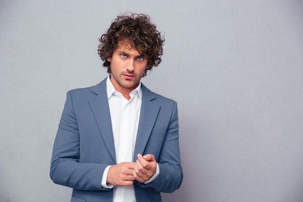 Portrait of a confident businessman looking at front over gray wall