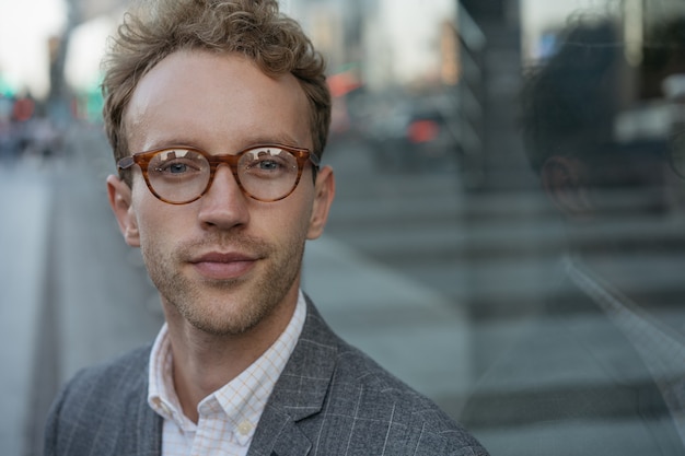 Portrait of confident businessman wearing stylish eyeglasses looking at camera on the street