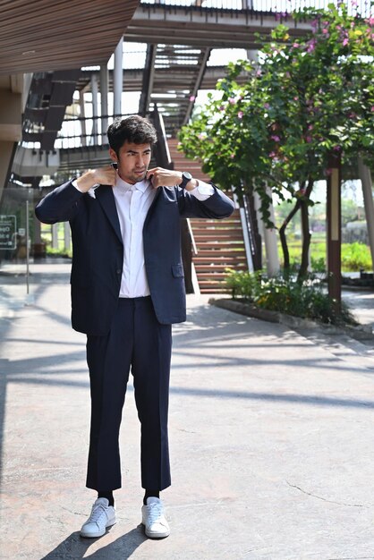 Portrait of confident businessman wearing stylish suit standing outside modern office building