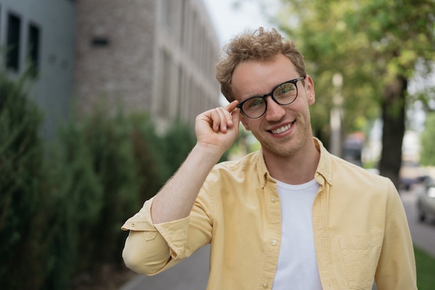 Portrait of confident businessman wearing yellow shirt  stylish eyeglasses standing on the street