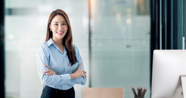 Portrait of Confident businesswoman standing with arms crossed and smiling at the camera in modern office room